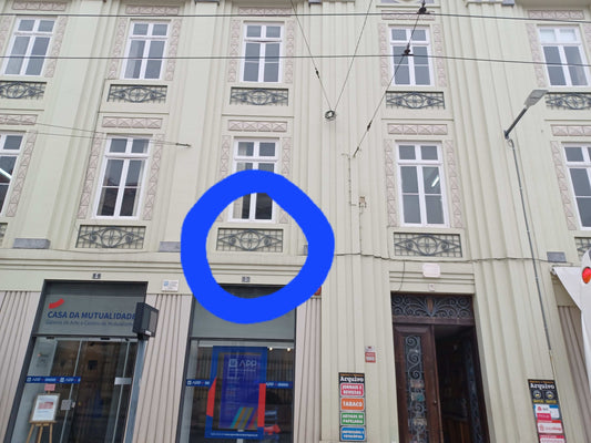 Building facade in Coimbra with a blue circle highlighting a decorative balcony design