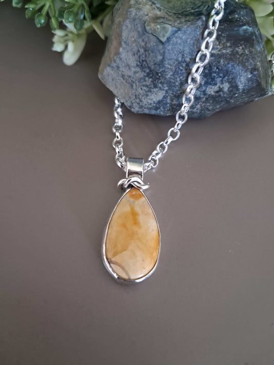 Necklace with a teardrop-shaped yellow jasper pendant on a gray surface.