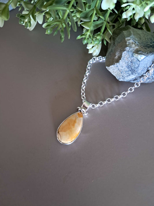 Necklace with a teardrop-shaped amber pendant on a gray background